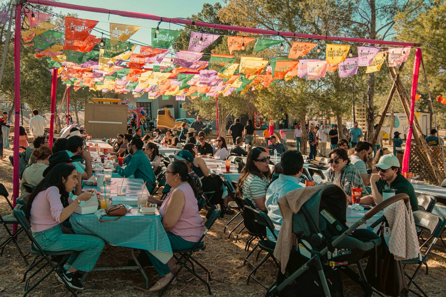 Familias en mesas largas bajo papel picado