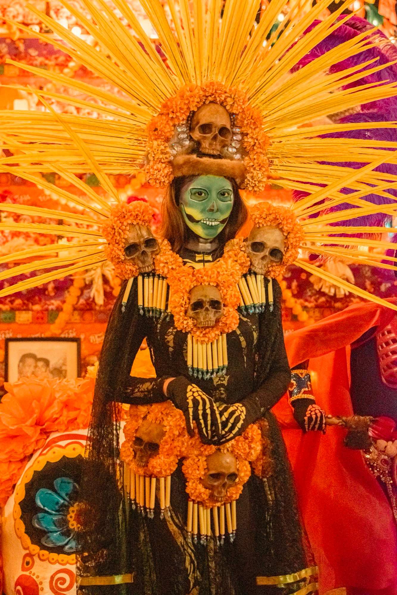 Catrina con penacho de rayos dorados frente al altar